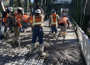 Workers place concrete for the deck of the new pedestrian bridge over the railroad tracks next to S Broad Street (2-7-2024 photo)