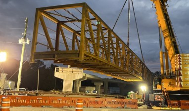 A crane lifts and maneuvers the steel pedestrian bridge into place over Cortez Blvd. (5-25-2023 photo)