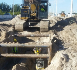 Workers install pipe in a trench box next to I-275