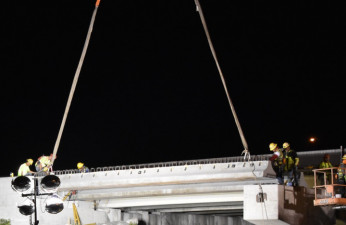 Workers guide a concrete beam into place where the northbound I-275 bridge is being widened over Sr 60 (3/21/2020 photo)