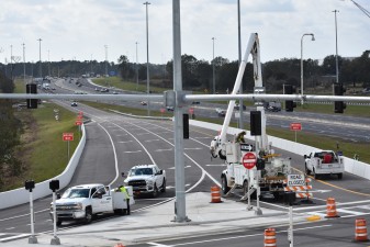 Crews doing work on signs and signals at the intersection of the northbound I-75 exit ramp and Overpass Road (1/13/2023 photo)