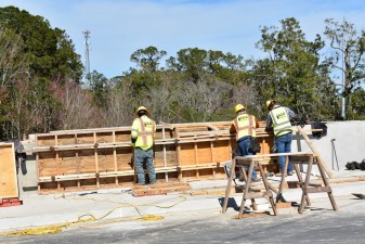 Workers build a concrete wall along westbound Overpass Road at I-75 (1/24/2022 photo)