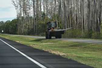 Carrying a load of removed signs on the pedestrian trail, south of the eastbound SR 50 lanes (12-9-2025 photo)
