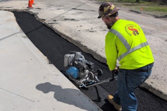 Black base asphalt is compacted around the rebuilt traffic separator at the Landfill Road intersection (3-5-2026 photo)