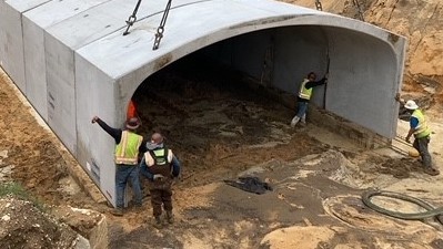 Placing underpass precast steel-reinforced concrete arch segment (6/25/2021 photo)