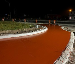 Red colored concrete is being placed for a truck apron to give extra room for tractor trailers driving through the roundabout (12/5/2022 photo)