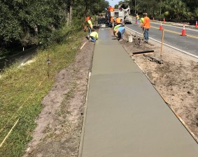 Crews are finishing freshly placed concrete for a sidewalk along N. Turkey Oak Drive, north of W. Balloon Lane (10/18/2021 photo)