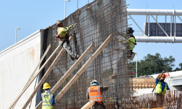 Workers tie steel for noise barrier wall