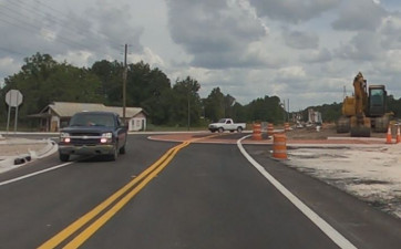 Driving south on US 98 at the roundabout construction at Trilby Road. Traffic is in a temporary alignment, using some of the roundabout's red concrete apron as the east side is built. (July 2, 2020 photo)