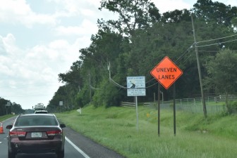 The orange road sign warns of uneven lanes ahead (7-21-2025 photo)